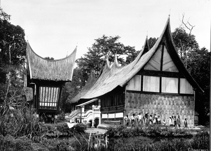 Historische foto van een rumah gadang met rijstschuren in West-Sumatra — het traditionele huis waarvandaan jonge mannen op merantau vertrokken