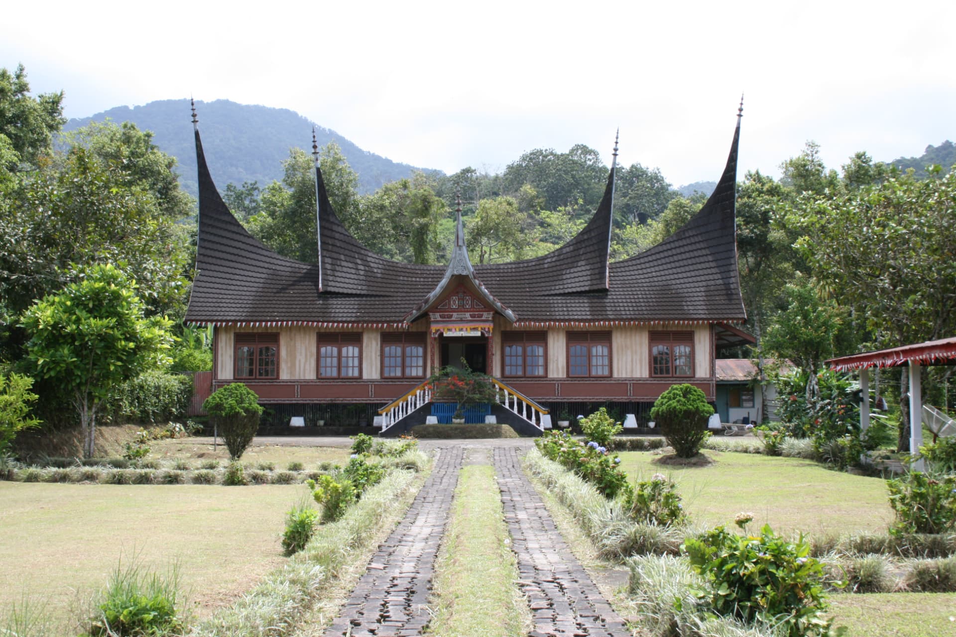 Traditionele Minangkabau rumah gadang met opstaande buffelhorendaken in een groen berglandschap